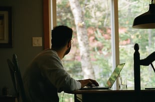 person seeking CKA certification sitting at a desk with a computer looking outside.